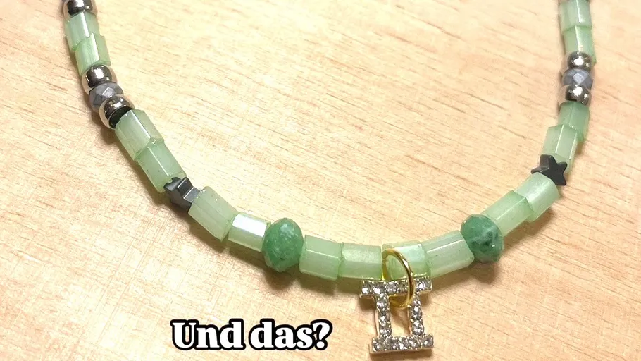 Perlenkette mit Zwillinge-Anhänger auf Tisch.