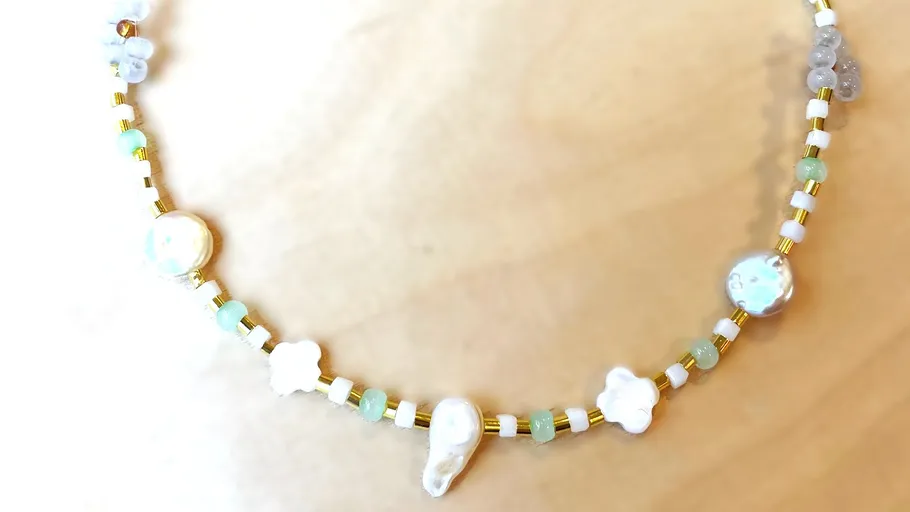 Beaded necklace with pearls on wood background.