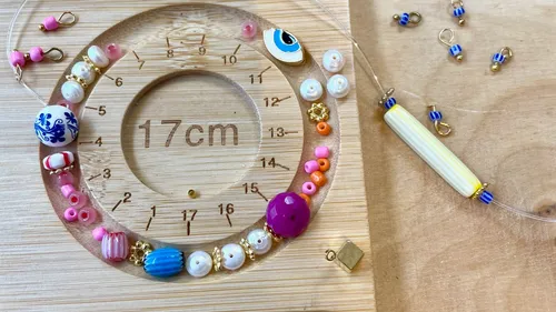 Beads and tools on wooden board for jewelry making.