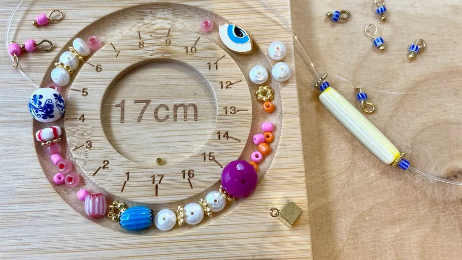 Beads and tools on wooden board for jewelry making.