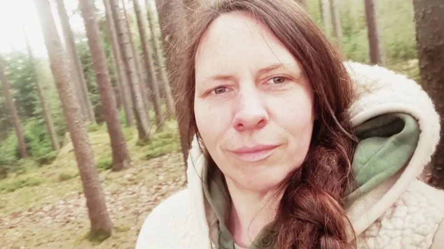 Frau im Wald mit Bäumen drumherum.