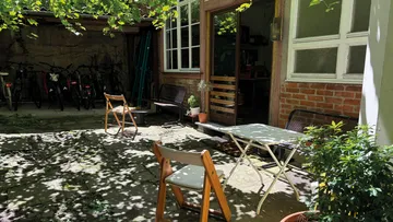 Outdoor patio with chairs and table, shaded area.
