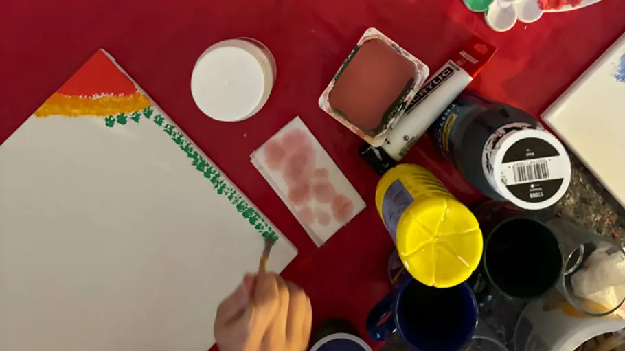 Hand painting on canvas with supplies nearby.