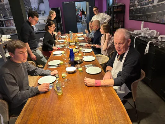 Group dining at long wooden table indoors.