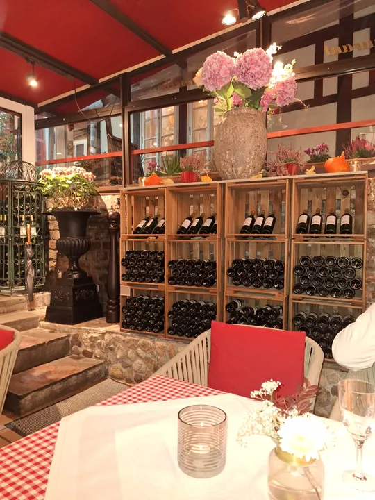 Weinflaschen auf Regalen in gemütlichem Restaurant.