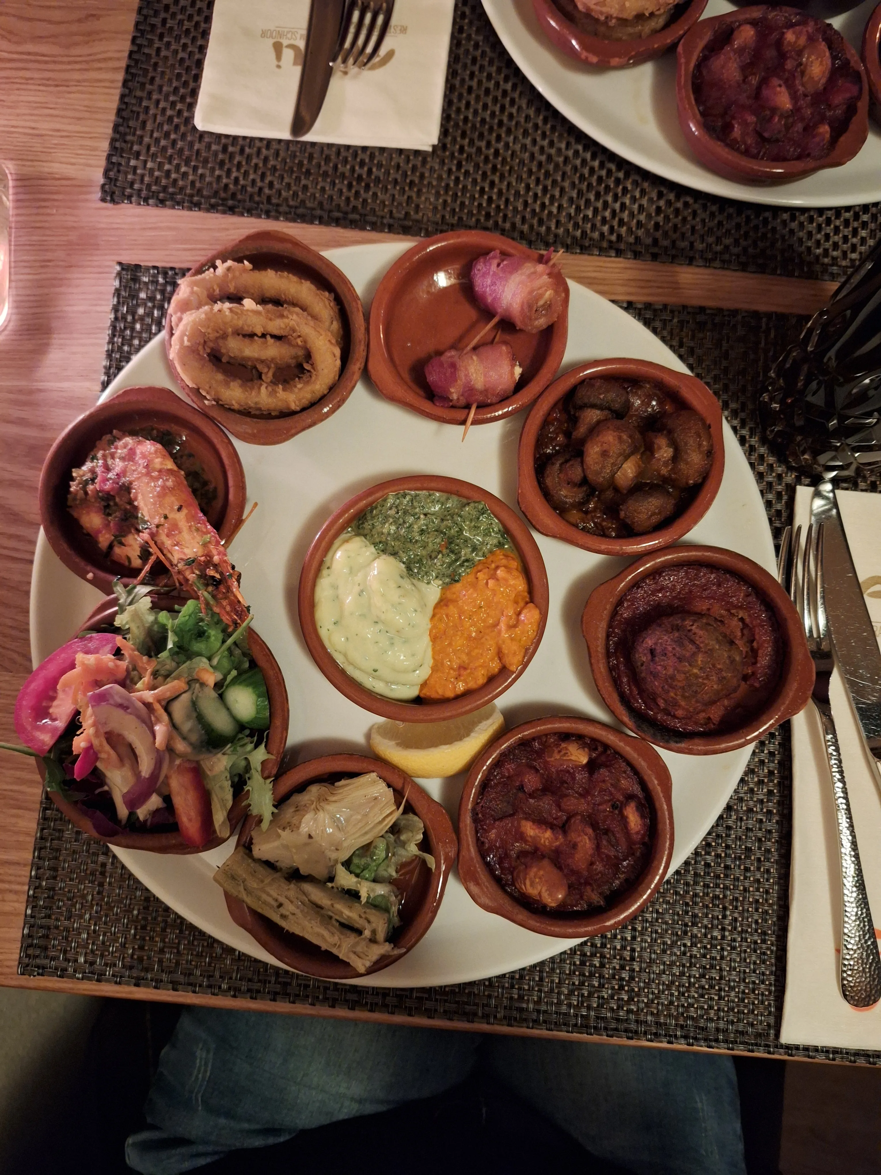 Verschiedene Tapas-Gerichte auf einem runden Teller.