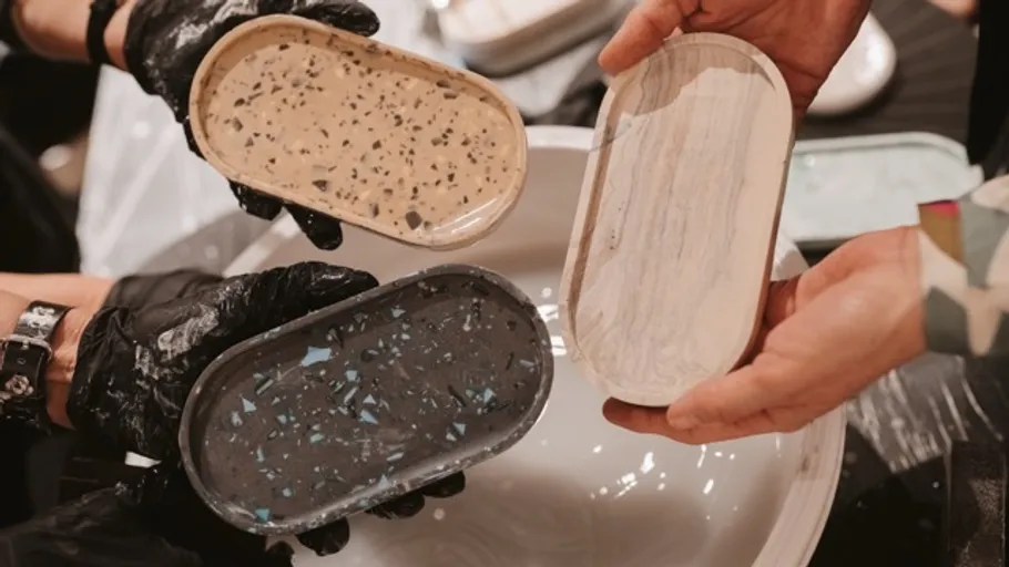 Hands holding three decorative trays indoors.