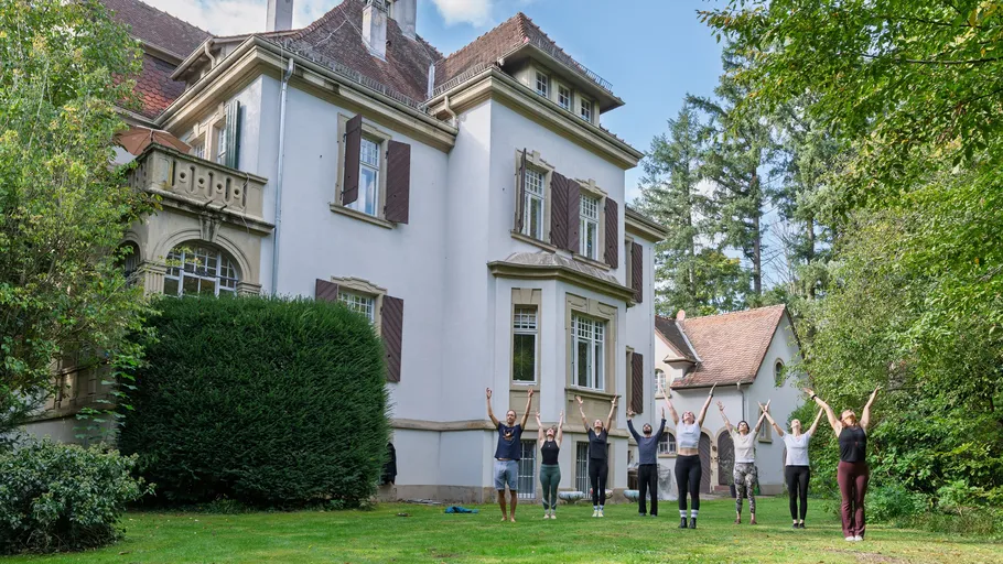 People exercising in front of a large house.