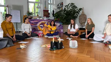 Gruppe meditiert mit Musikinstrumenten im Raum.