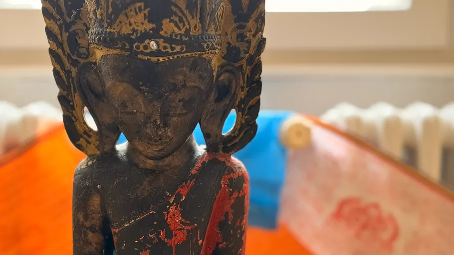 Wooden statue with intricate carvings, colorful background.