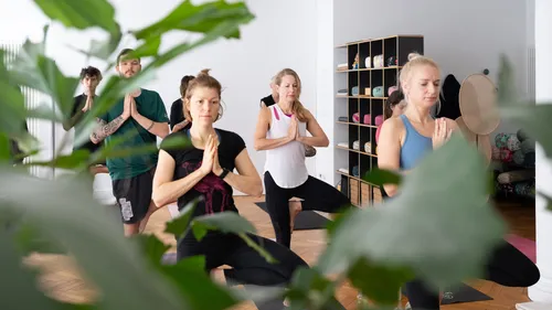 Group performing yoga in a studio with plants.