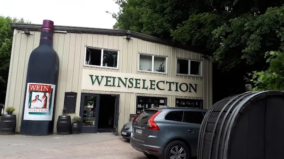 Building with wine shop sign, large bottle outside.