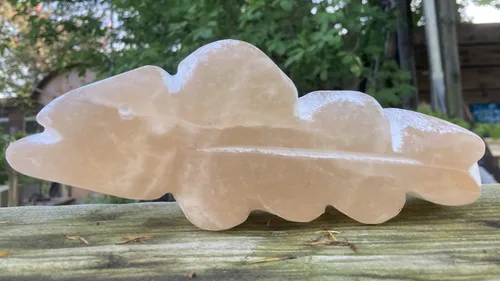 Stone fish sculpture on wooden surface outdoors.