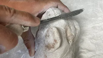 Hand schnitzt Stein mit Raspelwerkzeug.