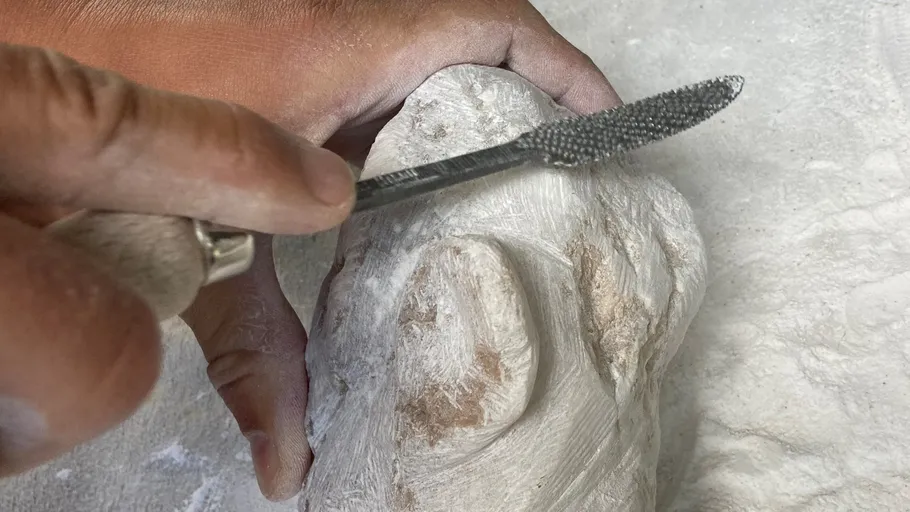 Hand carving stone with a rasp tool.