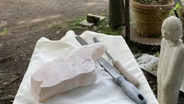 Steinblock und Werkzeuge auf Tisch im Freien.