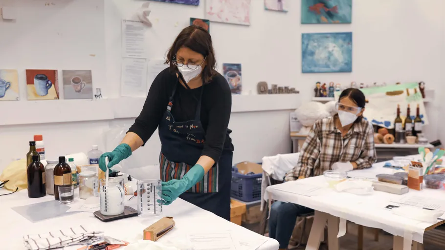 Two people working with art supplies in studio.