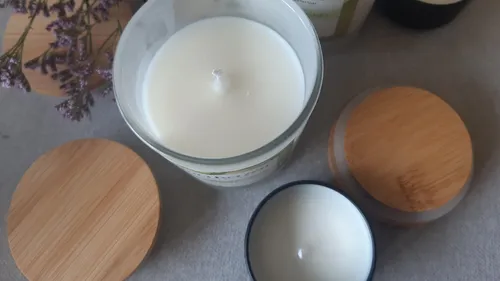 Weiße Kerzen mit Holzdeckeln auf Tisch.