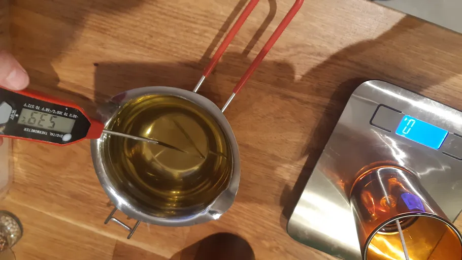 Thermometer in melted substance, digital scale nearby.