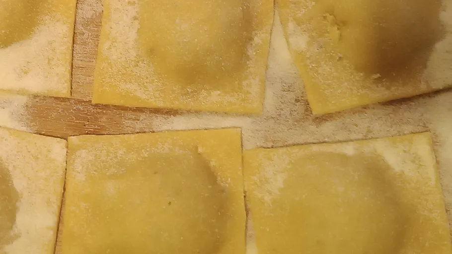 Quadratische Ravioli auf Holzoberfläche.