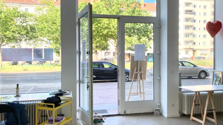Open glass door with street view, trees outside.
