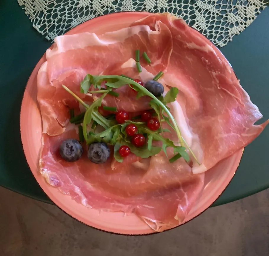 Plate with prosciutto, berries, and greens.