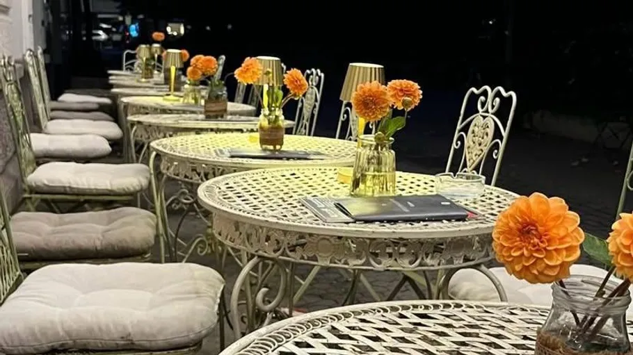 Outdoor cafe tables with flowers at night.