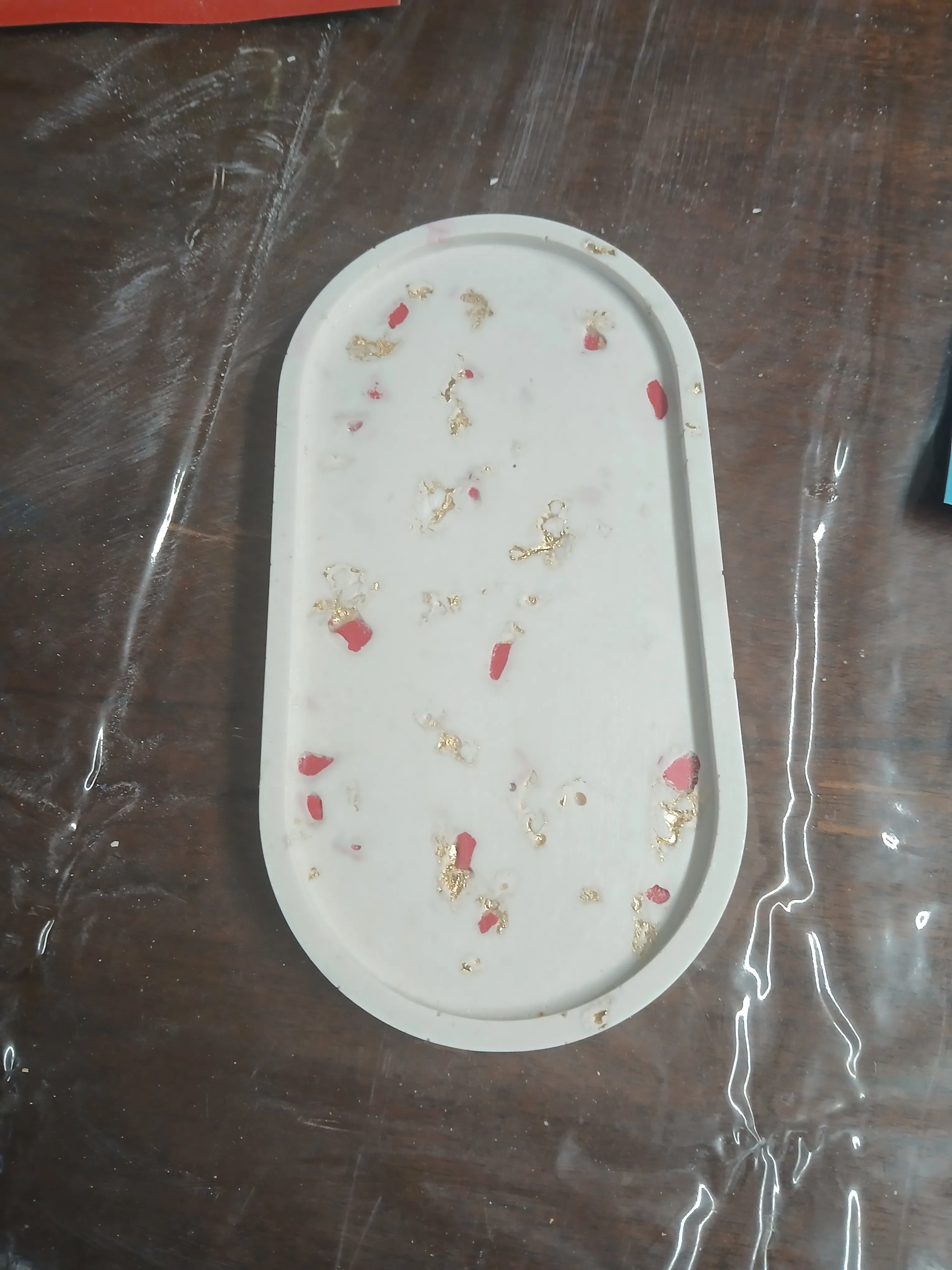 Weißes Tablett mit goldenen und roten Flecken.