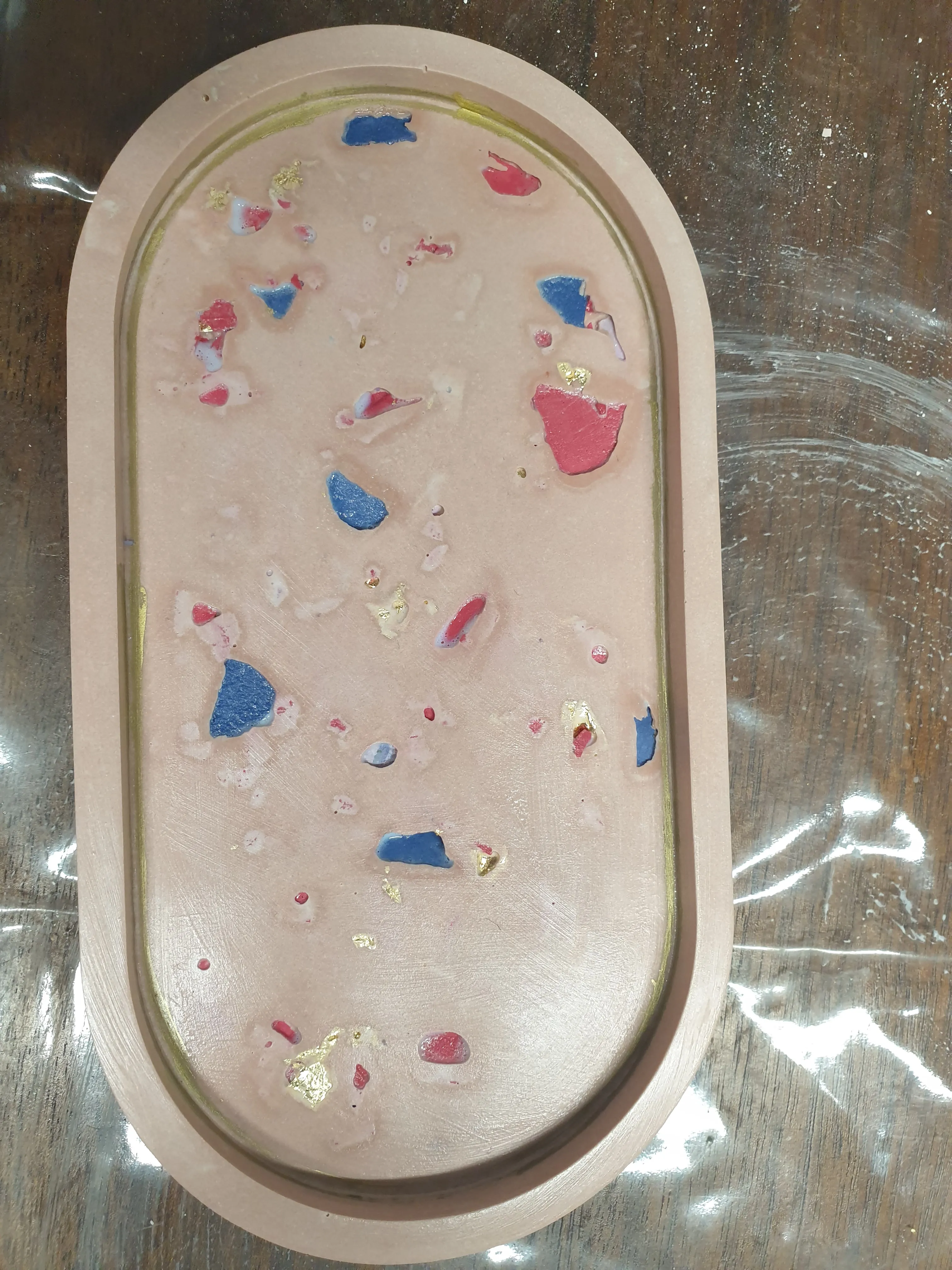 Ovales Tablett mit bunten Farbspritzern.