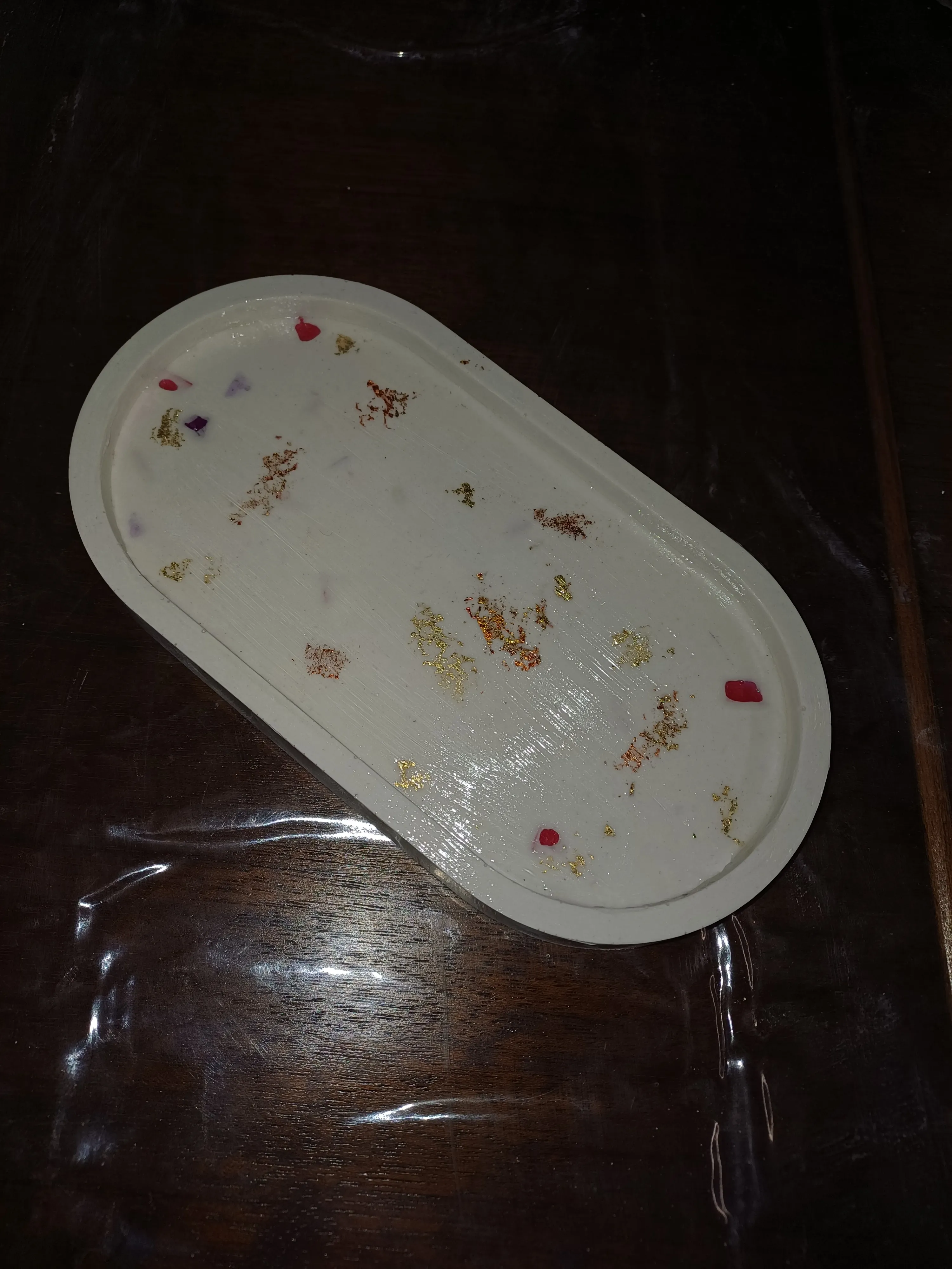 Weißes Tablett mit Dekosprenkeln, auf Holztisch.