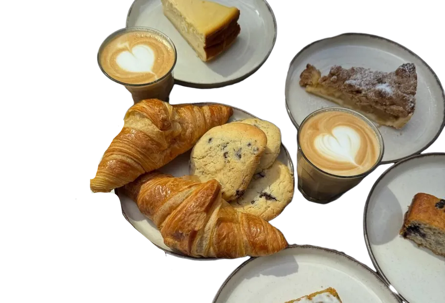 Croissants und Kaffee auf Tellern, Dessert ringsum.