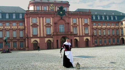 Person in historic costume outside large building.