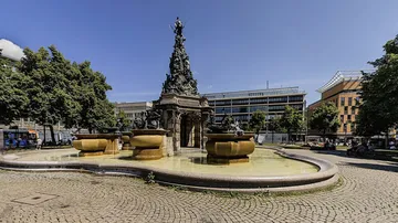 Large fountain with sculptures in city square.