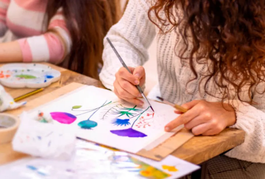 Person painting colorful flowers on paper.