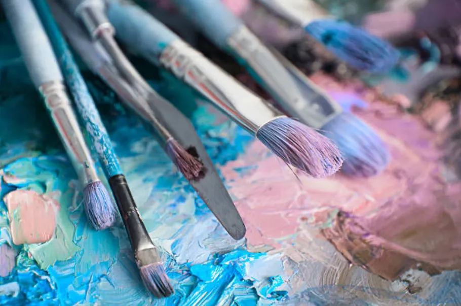Paintbrushes with pastel colors on palette.