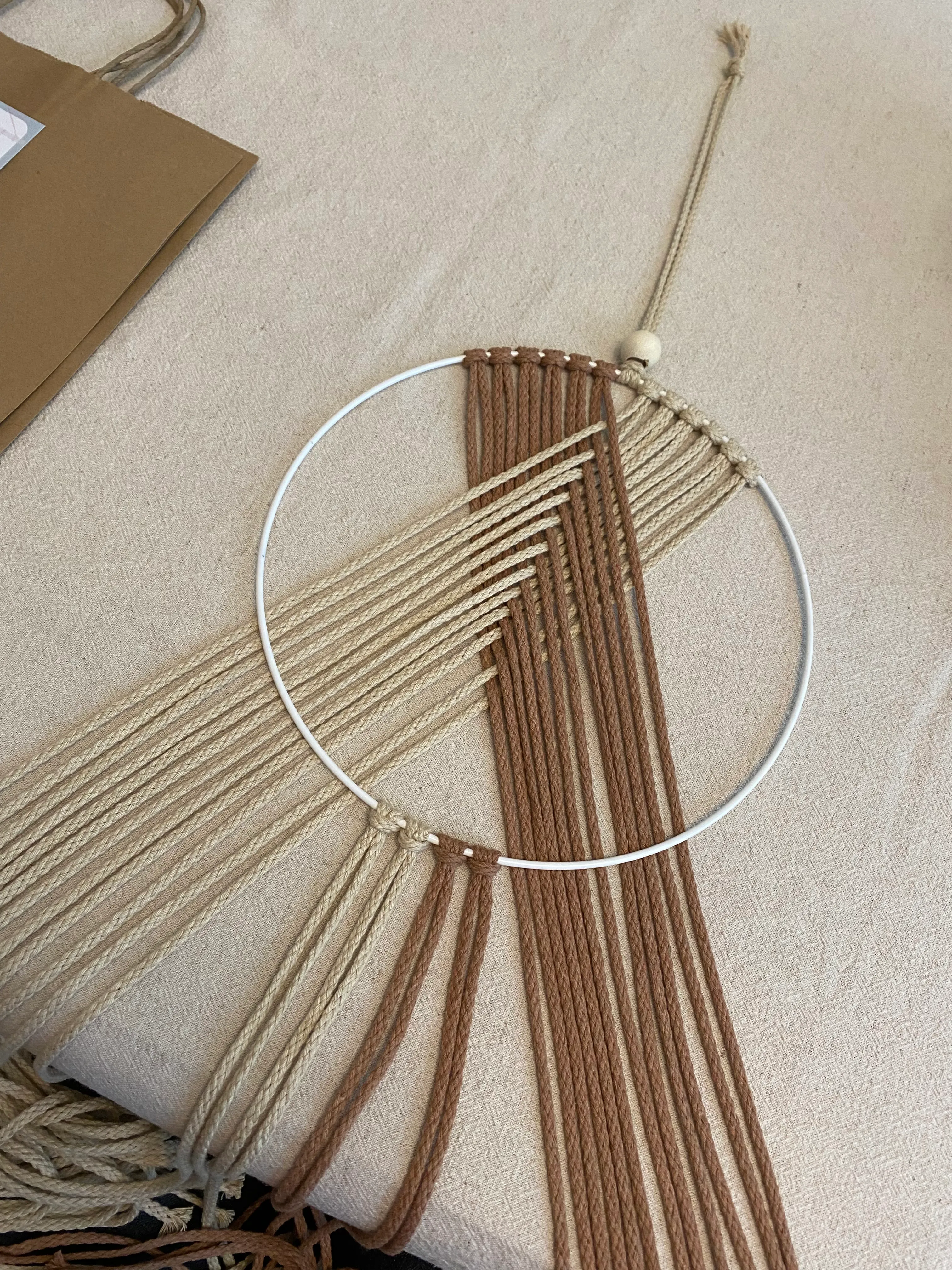 Macrame hoop with tan and brown cords.