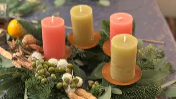 Four candles on decorative Christmas wreath.