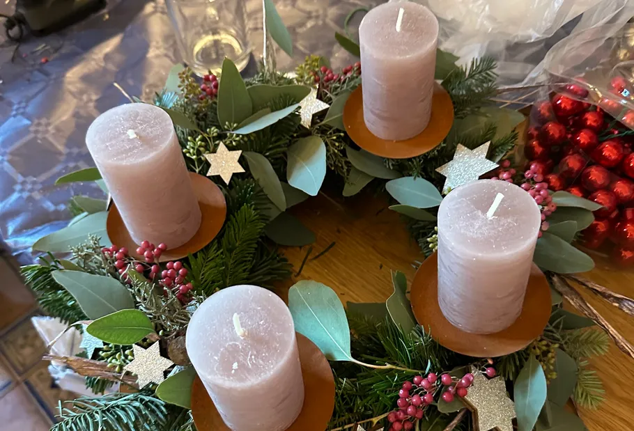 Candle wreath with greenery and red berries.