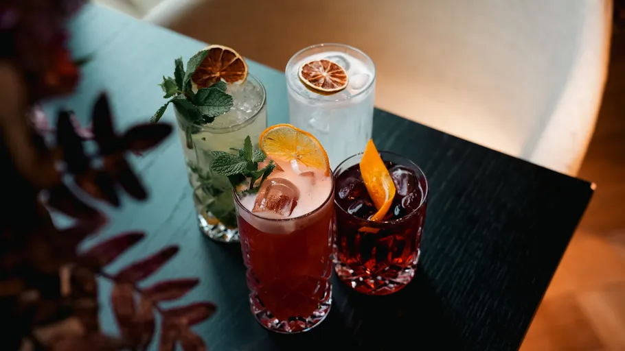Four colorful cocktails on a dark table.