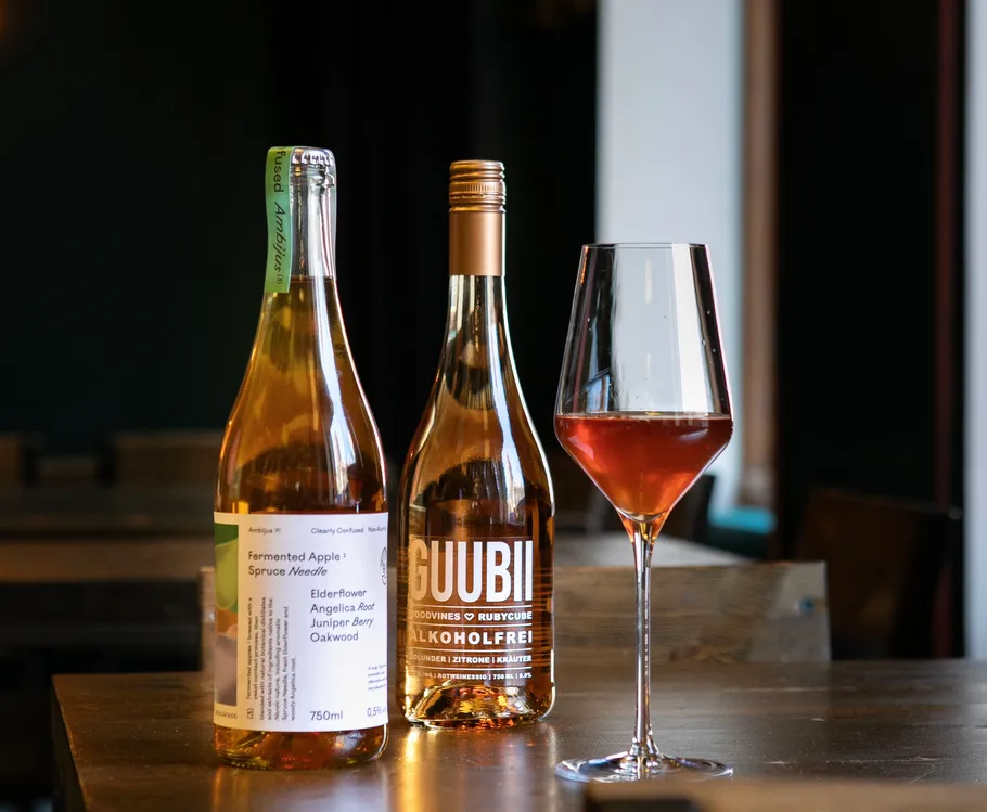Bottles and a wine glass on wooden table.