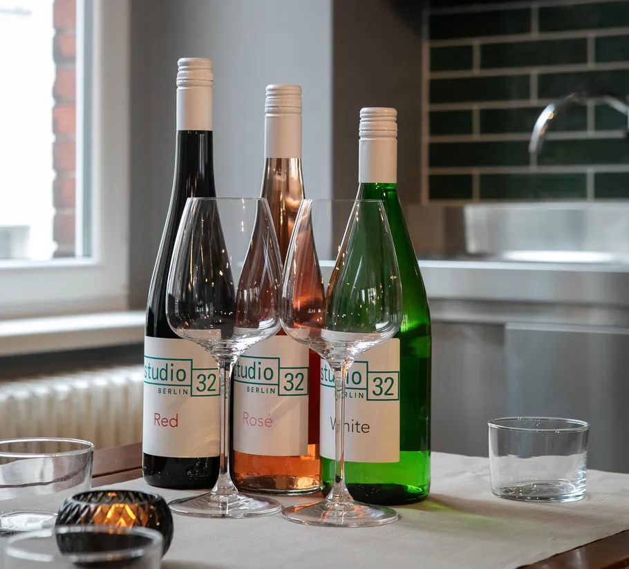 Three wine bottles and glasses on table.