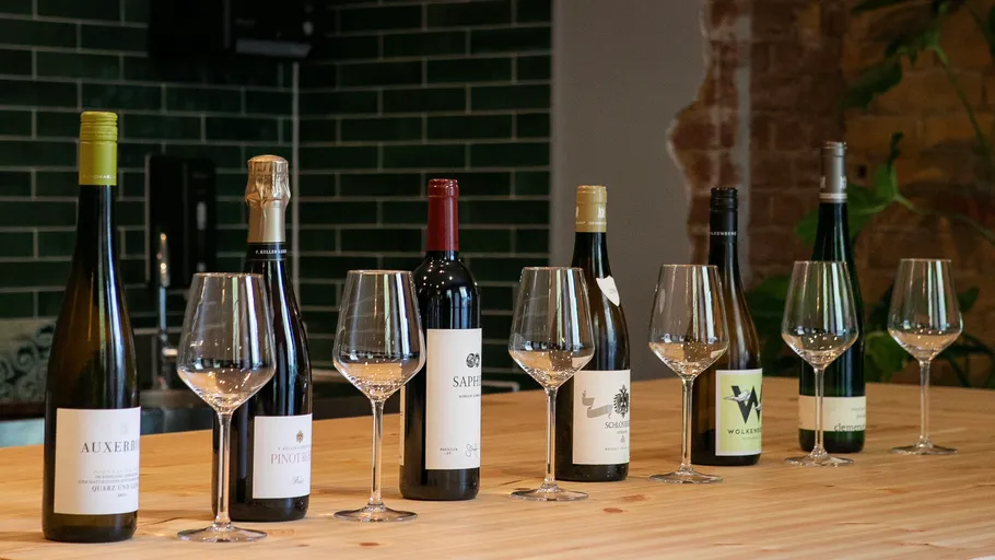 Seven wine bottles with glasses on table.