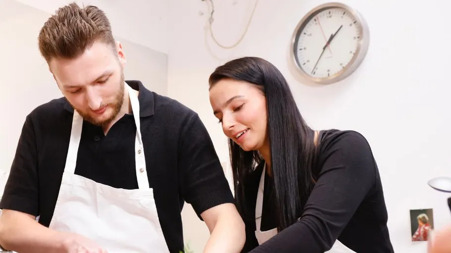 Two people cooking together in kitchen.