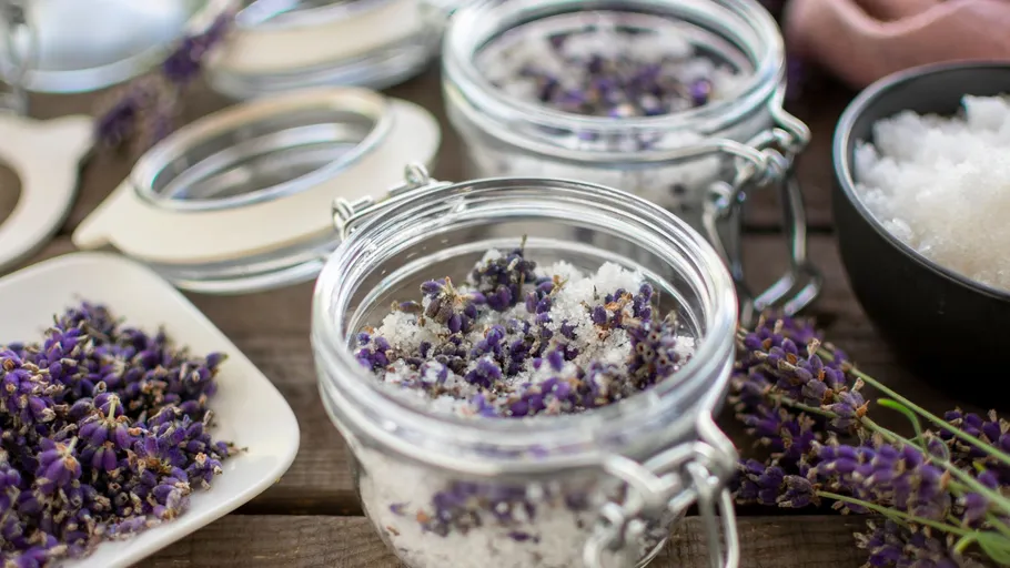 Gläser mit Lavendel-Badesalz auf Tisch.