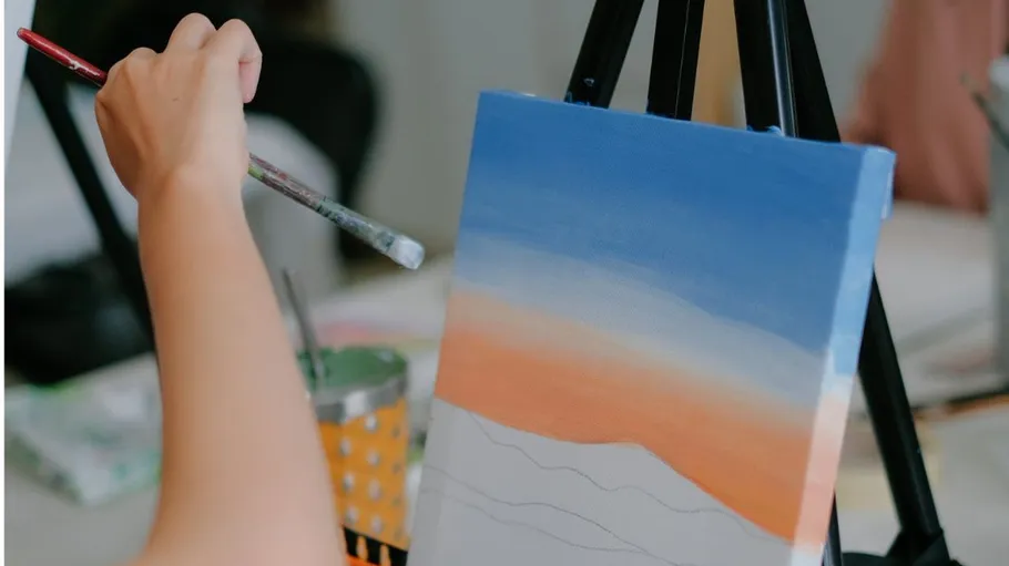 Hand painting canvas on easel indoors.