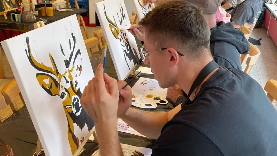 Person painting deer on canvas in studio.