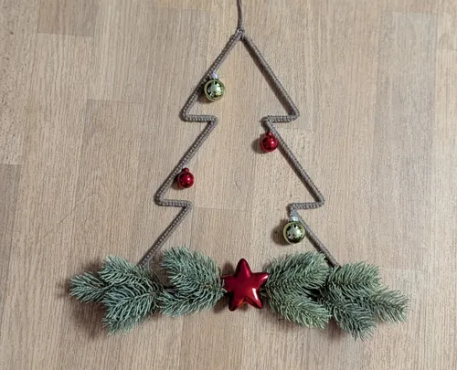 Wire tree decoration with baubles on table.