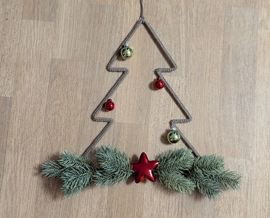 Wire tree decoration with baubles on table.