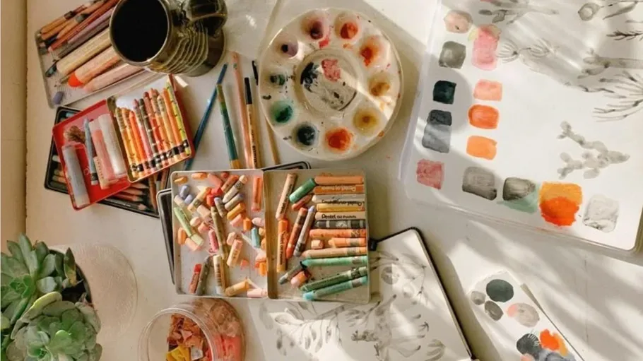 Art supplies arranged on sunlit table.