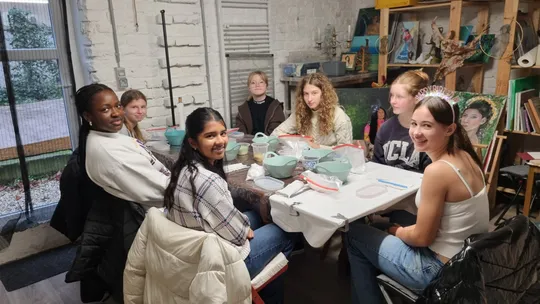 Gruppe Mädchen sitzt an einem Tisch drinnen.
